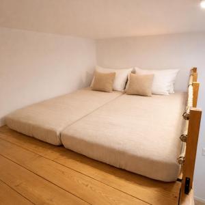a bed with white sheets and pillows on a wooden floor at Family Apartment near Mölltaler Gletscher 2 in Flattach