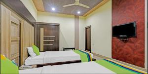 a bedroom with two beds and a flat screen tv at Hotel Apollo in Guwahati