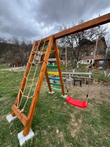 a playground with a ladder and swings in a field at CASA CRISAN in Vadu Crişului