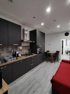 a kitchen with black cabinets and a table with a red couch at La Casetta di Nonno Settimo in Palermo