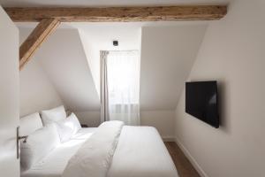 a bedroom with a white bed and a tv on the wall at Boutique Charme Apartments Küferstr 10-12 in Baden-Baden