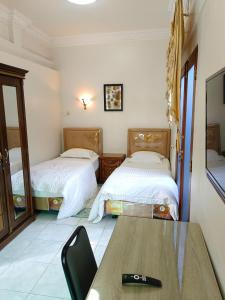 a room with two beds and a table with a remote control at Flamboyan House in Padang