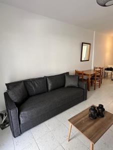 a living room with a black couch and a table at Seaside Paralio Apartment in Astros