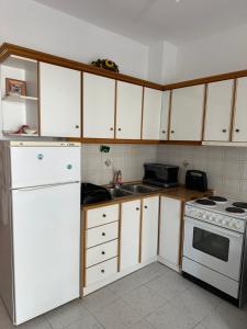 a kitchen with white cabinets and a stove and a sink at Seaside Paralio Apartment in Astros
