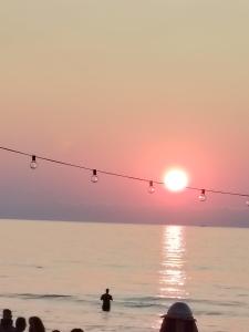 a group of people standing in the water watching the sunset at La Casetta di Nonno Settimo in Palermo