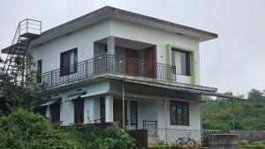 a white house with a balcony on top of it at Moms homestay 3 Bedrooms in Vagamon
