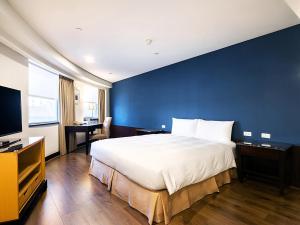 a bedroom with a large bed and a blue wall at Tempus Hotel in Taichung