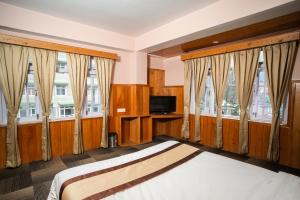 a bedroom with two beds and a tv and windows at Verdant The Vintage in Lachung
