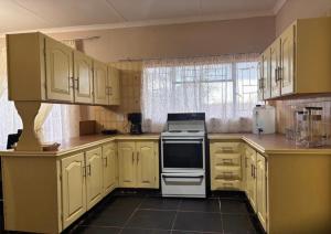 a kitchen with yellow cabinets and a white oven at Amatis House in Mokopane