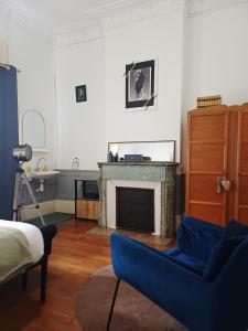 a living room with a fireplace and a blue chair at La Petite Porte Verte in Bouilland