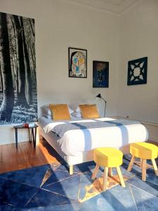 a bedroom with a bed and two yellow stools at La Petite Porte Verte in Bouilland