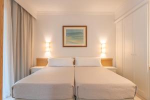 a bedroom with two beds and two lights on the wall at Caprice Vell Mari Hotel & Resort - New Opening 2026 in Can Picafort +64 photos