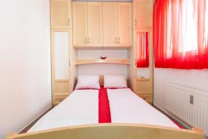 um pequeno quarto com uma cama com cortinas vermelhas em Apartment Crikvenica, Vinodol em Sopaljska