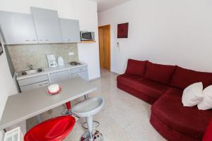 a living room with a red couch and a kitchen at Apartment Crikvenica, Vinodol in Sopaljska