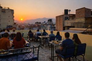 a group of people sitting at tables watching the sunset at FUNKY MONKEY- A Hostel, Hotel and Apartment in Kathmandu