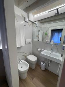 a white bathroom with a toilet and a sink at Hotel Adriatico in Venice +82 photos