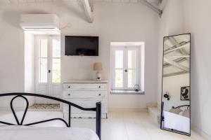a white bedroom with a bed and a mirror at Solea Cottage - Bright Escape in Skopelos in Skopelos Town