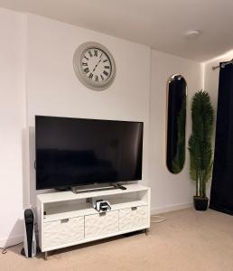 a living room with a tv and a clock on the wall at Springfield garden-Celtic park in Glasgow