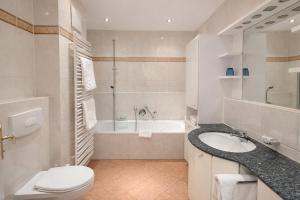 a bathroom with a tub and a toilet and a sink at Tivoli Apartments in Bad Reichenhall +89 photos