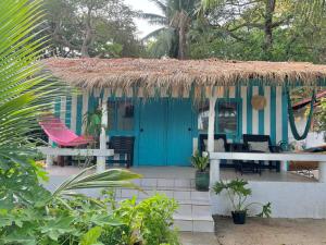 a blue house with a thatched roof and chairs at Benny beach house in Ko Samed
