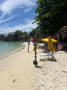 a sandy beach with chairs and umbrellas and the ocean at Benny beach house in Ko Samed +2 photos