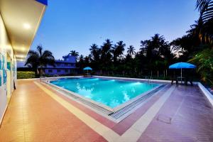 a swimming pool with blue umbrellas next to a house at Royal Garden Brindavan Resort in Hosa Kannambādi