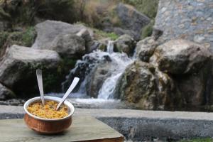 a bowl of food sitting on a table in front of a waterfall at Babutaal Resort in Chakrāta