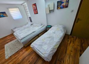 two beds in a room with a wooden floor at Lira Apartmani in Prnjavor