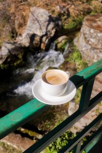 a cup of coffee sitting on a rail next to a river at Babutaal Resort in Chakrāta