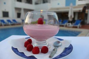 un vaso de bebida rosa con una frambuesa en un plato en Vicentina Hotel, en Aljezur