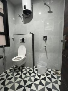 a bathroom with a toilet and a black and white checkered floor at Bhavya Guest House in Rīngas +15 photos