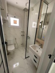 a white bathroom with a toilet and a sink at Sohag luxury apartment in Awlād Gharīb