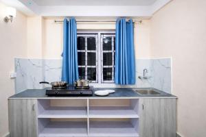 a kitchen with blue curtains and a stove and a sink at FUNKY MONKEY- A Hostel, Hotel and Apartment in Kathmandu