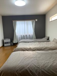 zwei Betten in einem Schlafzimmer mit Fenster in der Unterkunft Bon Clair in Sunagawa