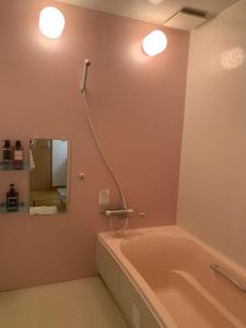 ein Badezimmer mit Badewanne und zwei Wandleuchten in der Unterkunft Bon Clair in Sunagawa + 32 Fotos