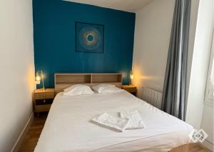 a bedroom with a white bed with a blue wall at Le Bailly charmant T2 Confort calme hyper centre in Orléans