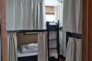 a group of bunk beds in a room with curtains at IZA Kamakura Guest House and Bar in Kamakura