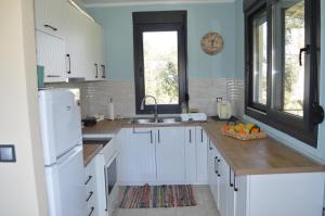 a kitchen with white cabinets and a sink and a window at Arethousa House in Nea Vrasna