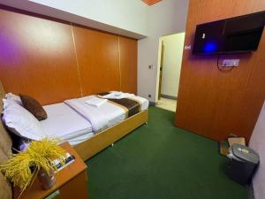a hotel room with a bed and a flat screen tv at Hotel Rosewood Uttara in Kāmarpāra