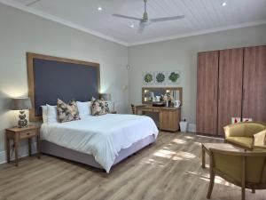 a bedroom with a large white bed and a chair at Milner Manor in Grahamstown