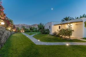 a garden with a stone wall and a house at Palatiana Agriturismo-Philoxenia Cottages Retreat in Galini