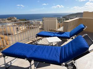 two blue chairs on a balcony with a view of the ocean at Welcome Apartment 13 in Għajn Melel