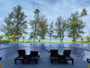 a pool at the resort with chairs and palm trees at Sematan Roxy Beach Apartment in Sematan
