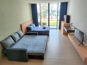 a living room with a couch and a bed and a tv at Sematan Roxy Beach Apartment in Sematan