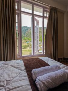a bed in a bedroom with a large window at Taleries Stays in Dirang Dzong