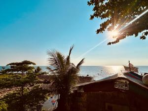 a view of a beach with a palm tree and the sun at Tchin tchin Guesthouse in Ko Chang +31 photos