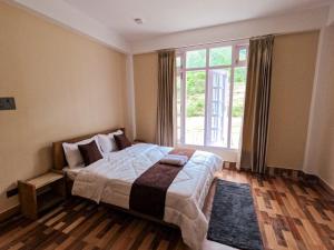 a bedroom with a large bed and a large window at Taleries Stays in Dirang Dzong