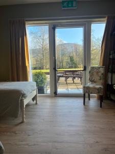 a bedroom with a bed and a sliding glass door at The Hermitage Riverside House in Clogheen