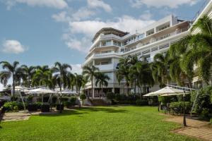 a large white building with palm trees in front of it at Hotel Cardoso in Maputo