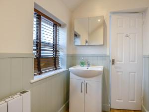 a white bathroom with a sink and a mirror at The Gables Studio in Keswick